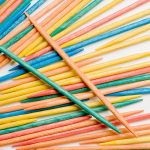 Extreme close-up of multi-colored tooth picks scattered on a white background.